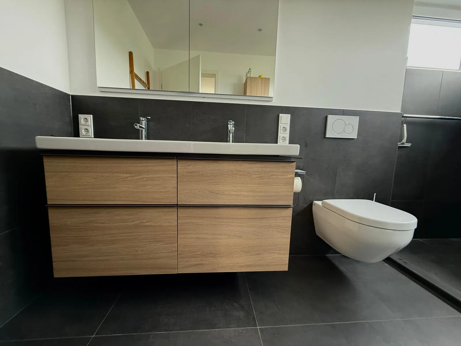 Badezimmer mit Doppelwaschtisch, Holzfurnier-Unterschrank und großformatigen anthrazitfarbenen Fliesen, Projekt in Mainz